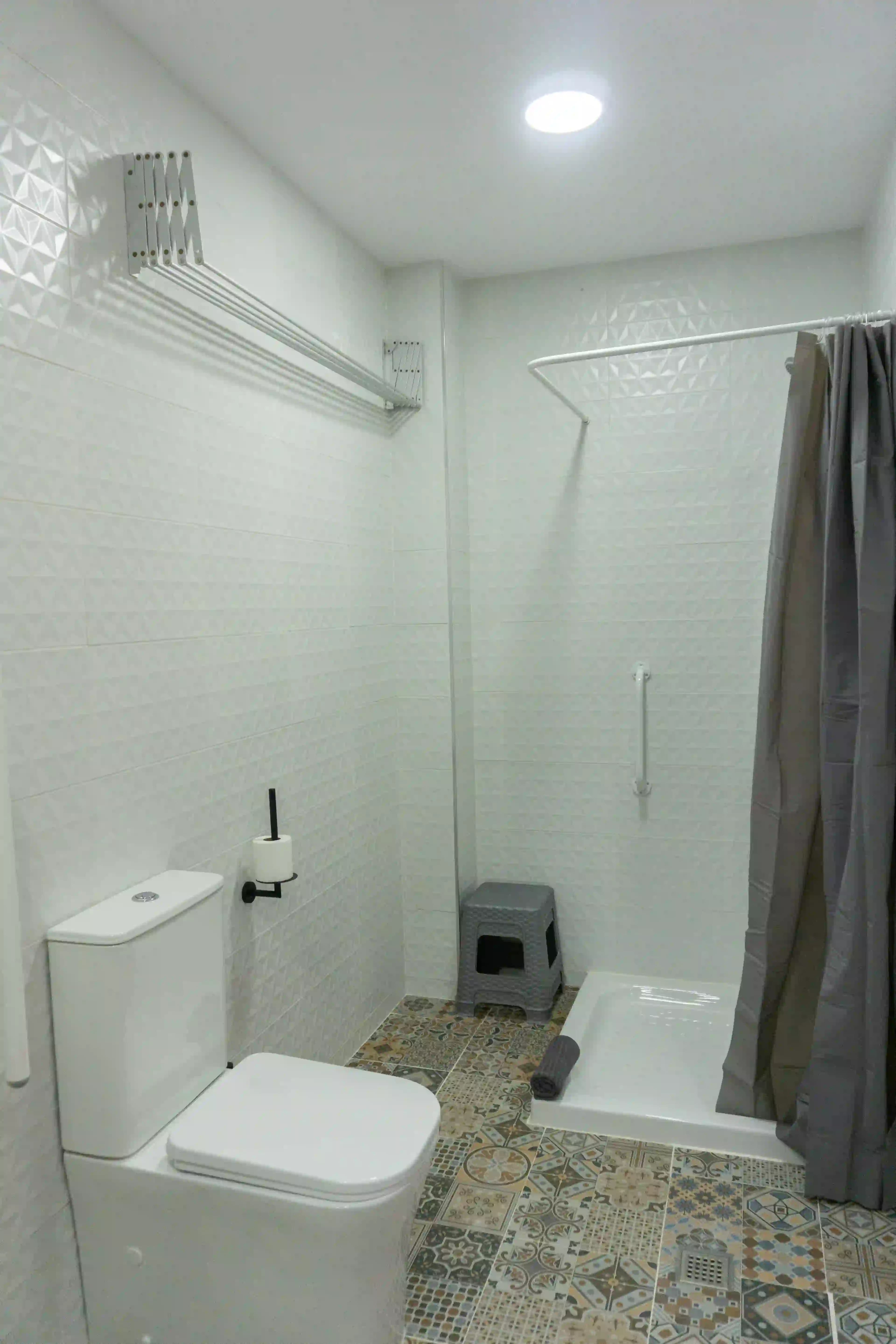 The accessible bathroom in room 10 at Hotel Apartamentos La Ruta, with a step-free shower tray, grab rails and a shower stool