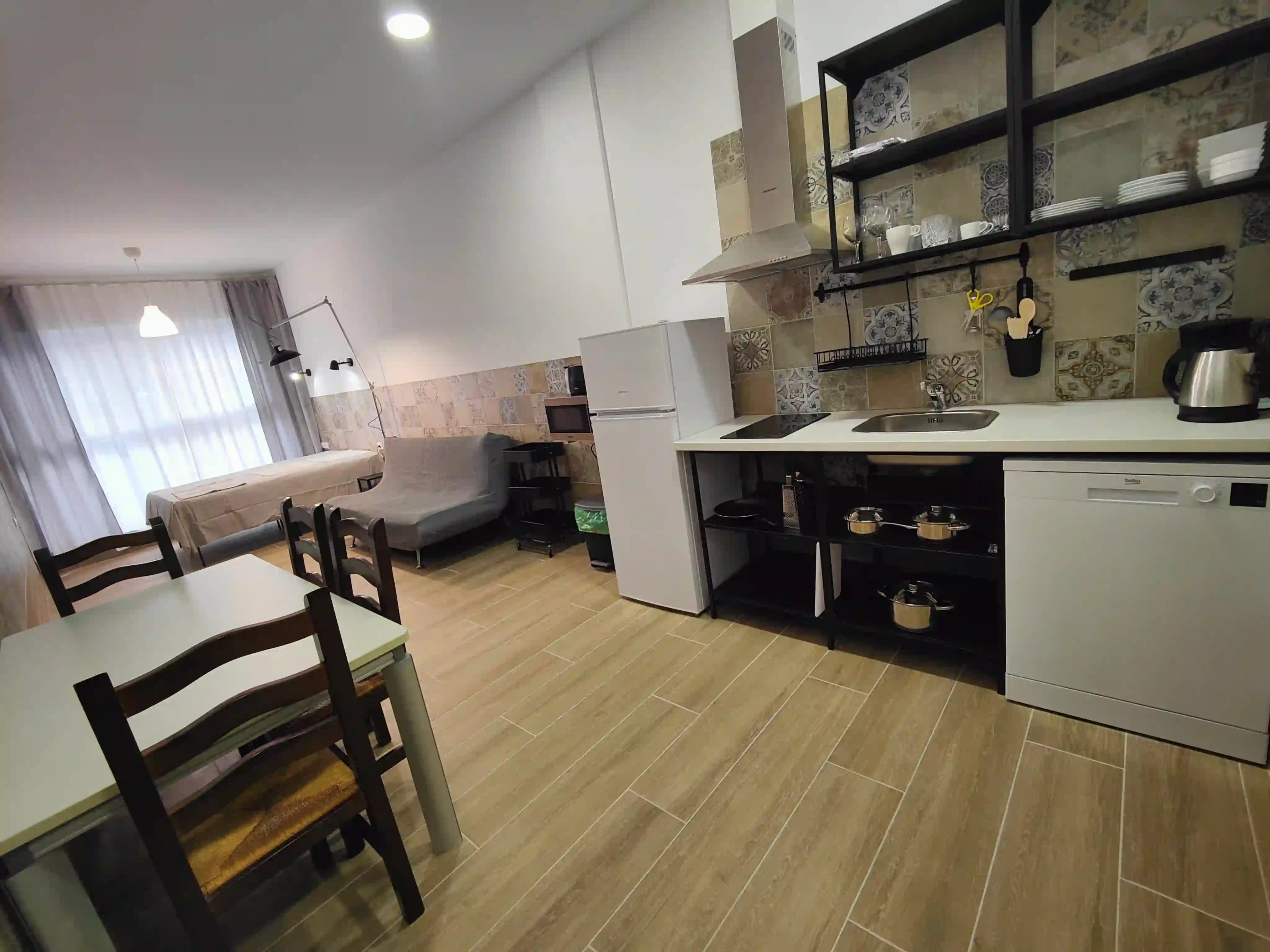 The kitchen and living end of a Pueblo Mar studio, with the sofa bed, a dining table and the double bed by the window